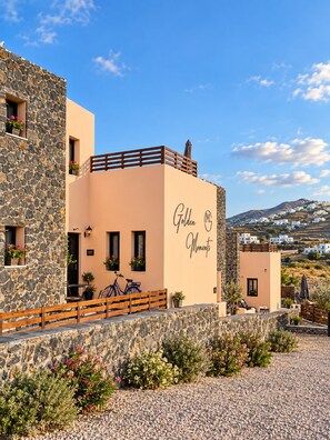 A building with a stone facade and a flat roof with a wooden railing. There is a sign on the building that reads 'Golden Moments.' - RHAPSODY Villa | Private Heated Hot Tub, Sea Views & 2 Bedrooms (Mesaria)