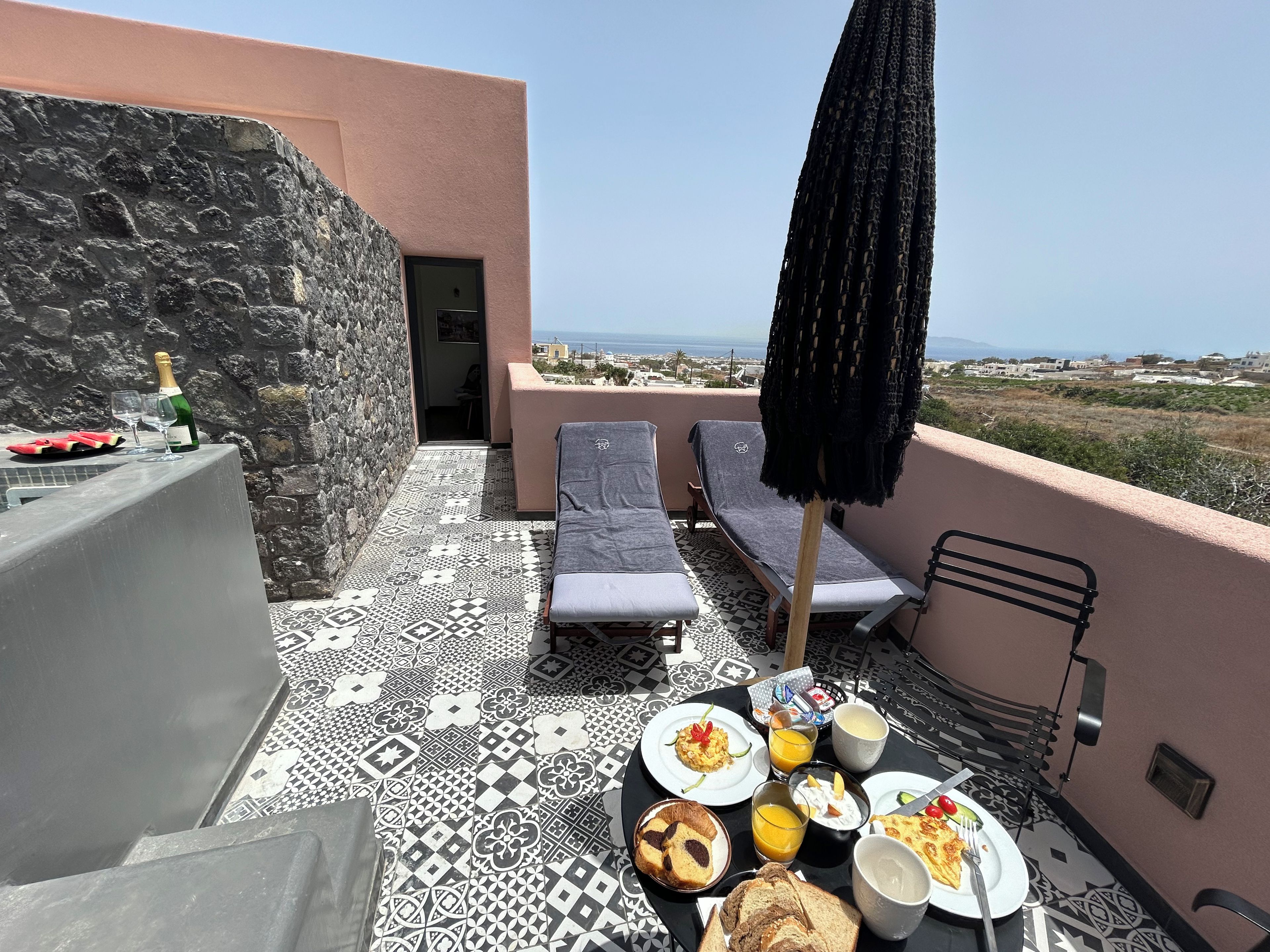 Eine Terrasse mit Frühstückstisch, Lounge-Stühlen und Meerblick.