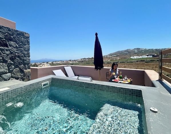 A swimming pool with clear water, a stone wall, and a view of a distant landscape.