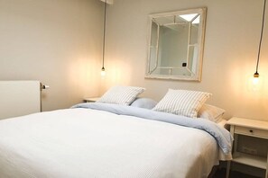A bedroom with a bed, bedside tables, a mirror, and pendant lights. - Studio Tol Zandvoort (Zandvoort)