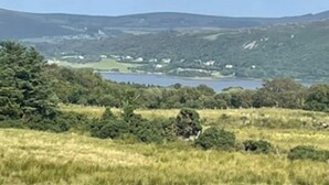 A rural landscape with a lake, hills, and scattered houses.