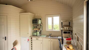 A compact kitchen with a sink, a microwave, and a toaster. There is a window providing natural light.