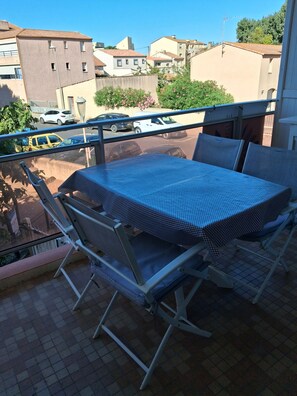 Ein Balkon mit Tisch und Stühlen, Blick auf die Nachbarschaft und eine Windkraftanlage in der Ferne.