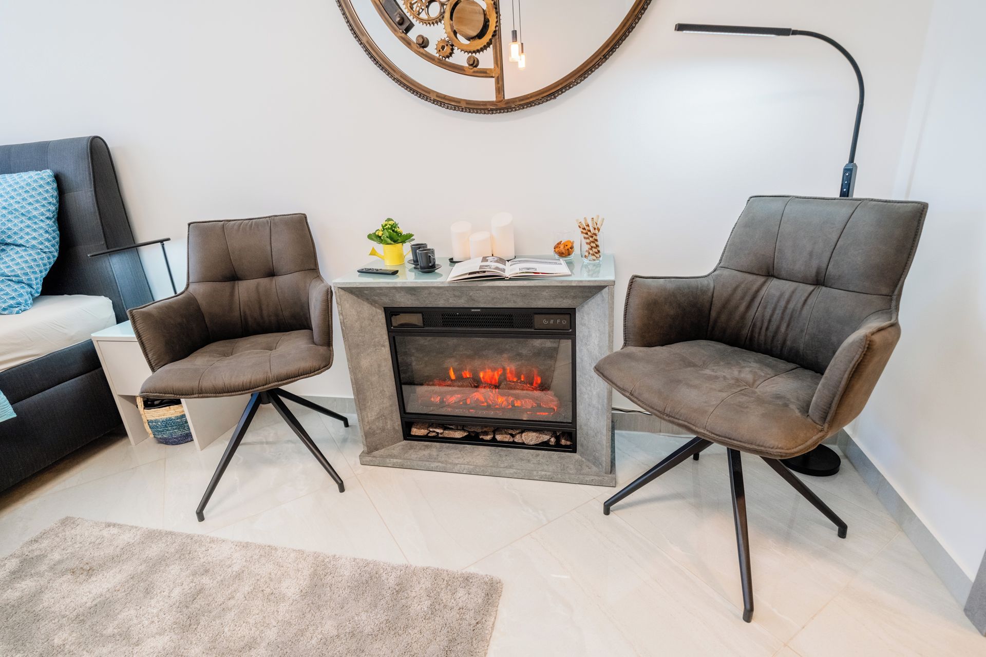 Ein modernes Wohnzimmer mit Kamin, zwei Ledersesseln, einem Couchtisch und einem Beistelltisch mit Dekoration.