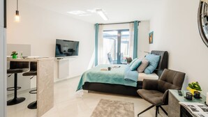 Ein modernes Schlafzimmer mit Bett, Fernseher, Schreibtisch und Stuhl.