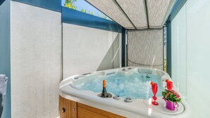 Ein Whirlpool mit Holzvertäfelung, eine Flasche und zwei rote Gläser.