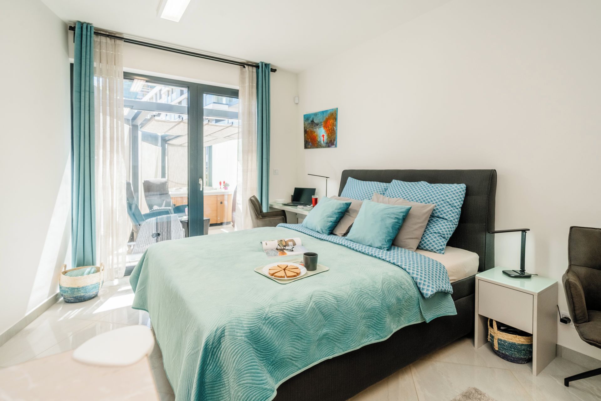 Ein Schlafzimmer mit einem Bett, einem Schreibtisch, einem Stuhl, einem Fenster mit Vorhängen und einem Gemälde an der Wand.