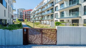 Ein moderner Wohnkomplex mit mehreren Balkonen, einem verschlossenen Eingangsbereich und einem Weg zu den Gebäuden.