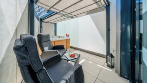 Ein moderner Außenbereich zum Sitzen mit Tisch und Stühlen, einem Whirlpool und Blick auf ein Gebäude.