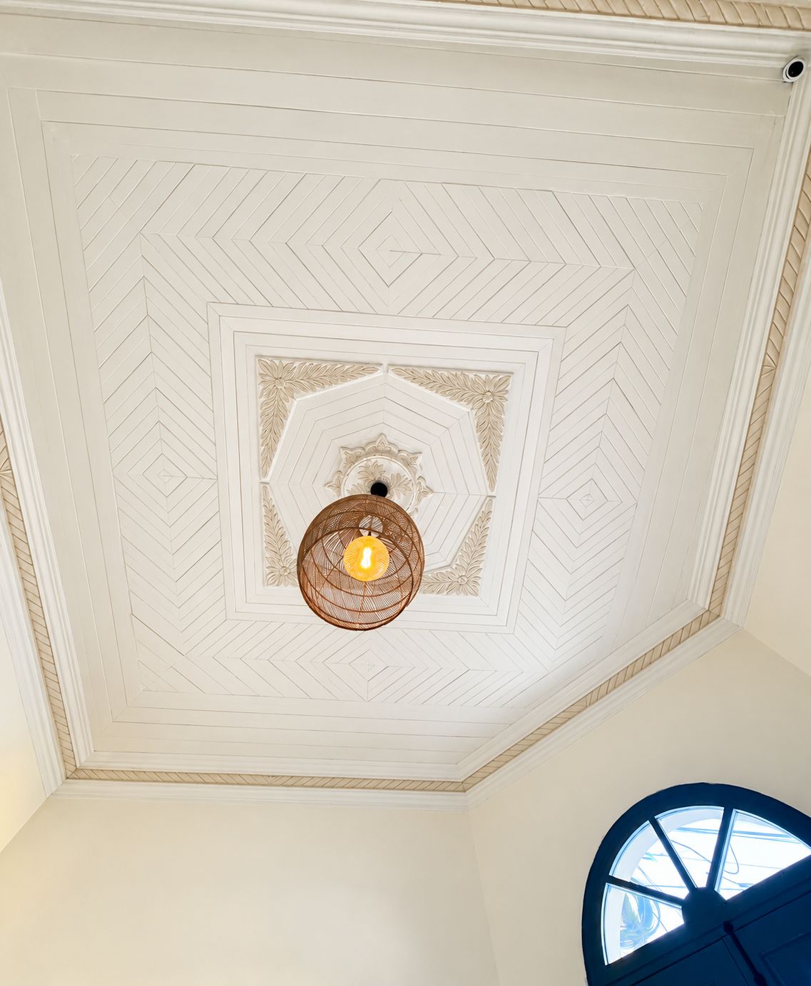 Een plafond met een geometrisch patroon en een centrale lamp.