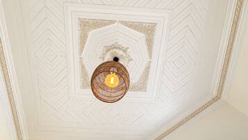 Een plafond met een geometrisch patroon en een centrale lamp.