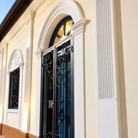 Fachada de edificio con ventanas arqueadas y una reja de metal negro.