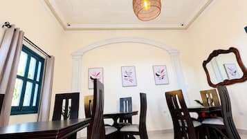 A dining area with a high ceiling, a chandelier, and a large mirror on the wall.