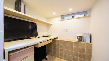 Cocina compacta con televisión de pantalla plana, cafetera y una ventana pequeña.
