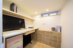 A compact kitchen with a flat-screen TV, a coffee maker, and a small window.