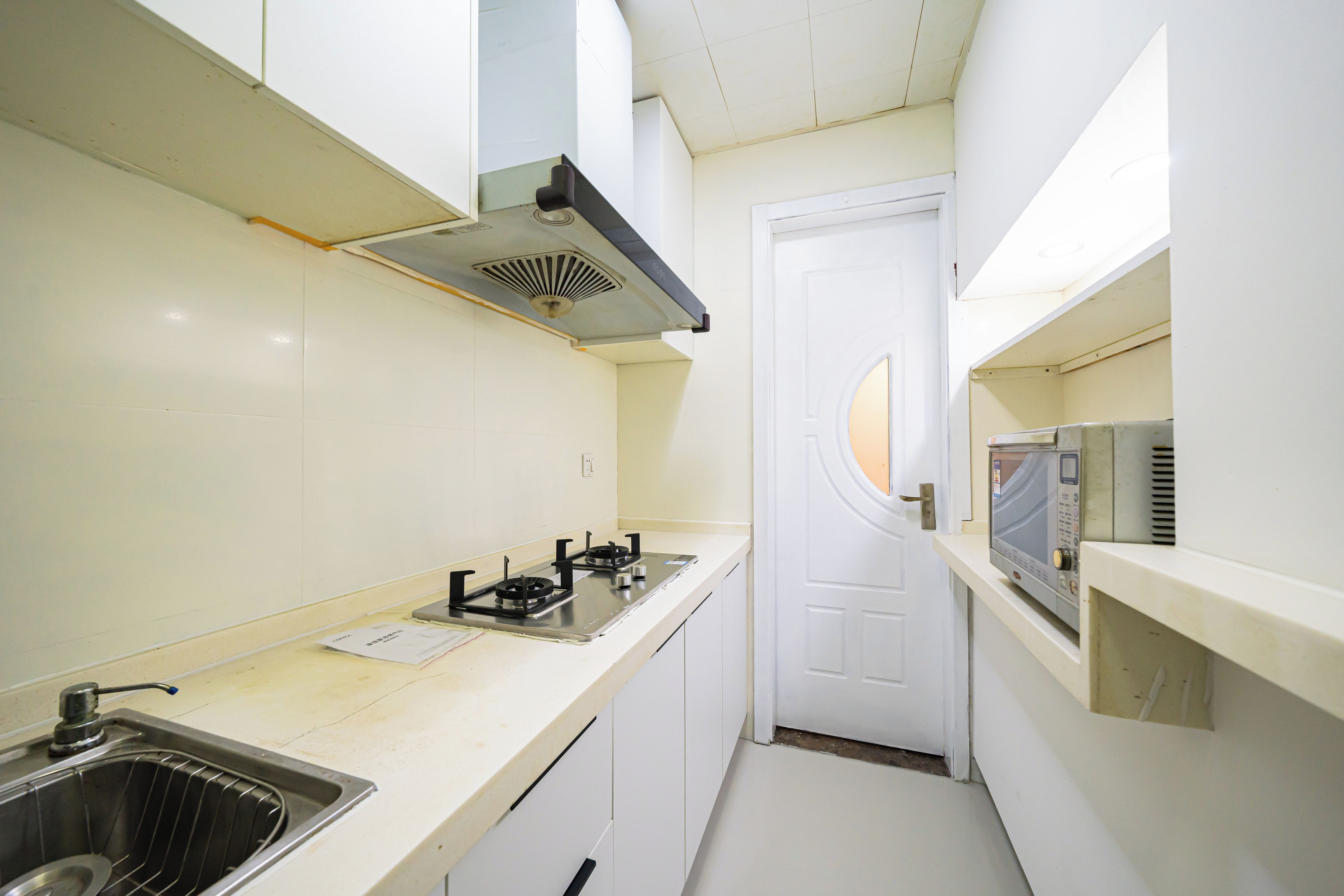 Cocina compacta con estufa a gas, microondas y pileta.