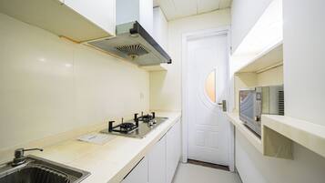 Cocina compacta con estufa a gas, microondas y pileta.