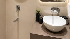 Ein modernes Badezimmer mit einem runden Spiegel, einem weißen Waschbecken und einer Dusche.