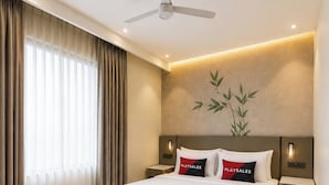 Ein modernes Hotelzimmer mit einem großen Bett, einem Standventilator, einer Couch und einer Wandlampe.