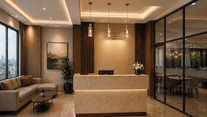 Eine moderne Hotelhalle mit einer Rezeption, einer Sitzecke und Blick auf die Stadt durch große Fenster.