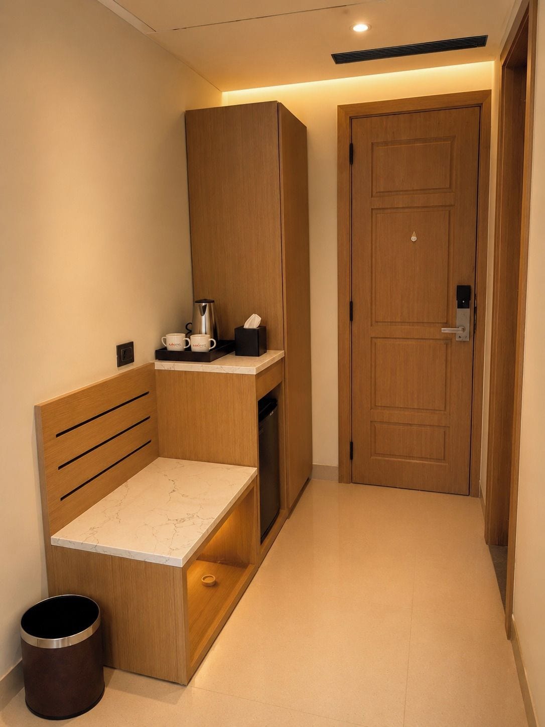 A compact room with a bed, a small table, a cabinet, and a door.