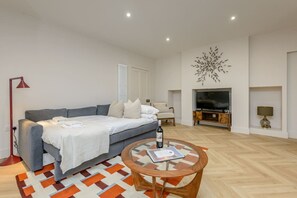 A modern living room with a sofa, a coffee table, a television, and a decorative wall piece. - Central Stylish 1 Bed | Near Stockbridge (Edinburgh)