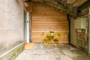 A small room with a wooden wall, a stone floor, and a table with two chairs. - Central Stylish 1 Bed | Near Stockbridge (Edinburgh)