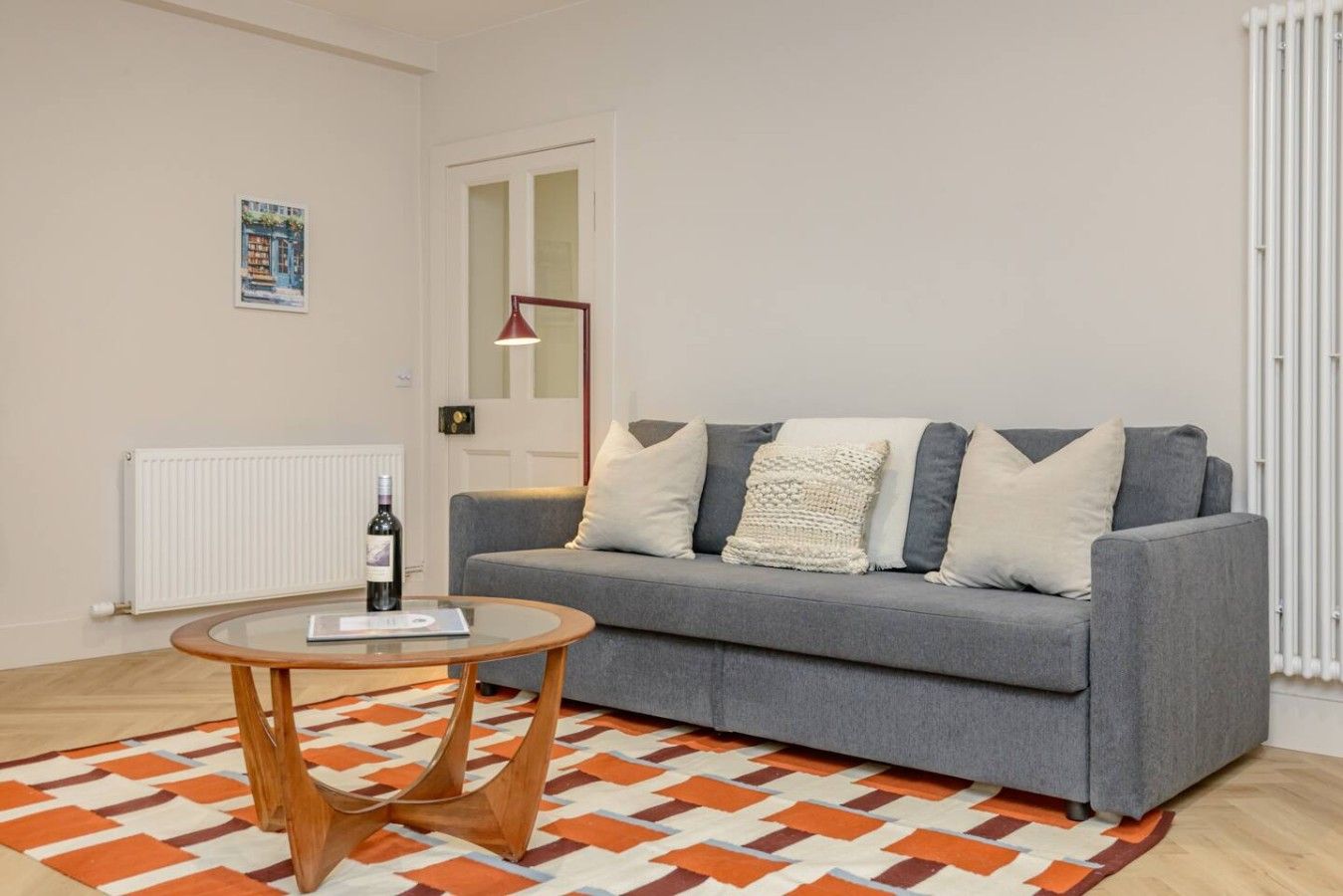 A living room with a grey sofa, a round wooden coffee table, and a patterned rug.