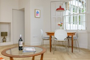 A room with a round glass table, a dining table with chairs, a red pendant light, and a window with curtains. - Central Stylish 1 Bed | Near Stockbridge (Edinburgh)