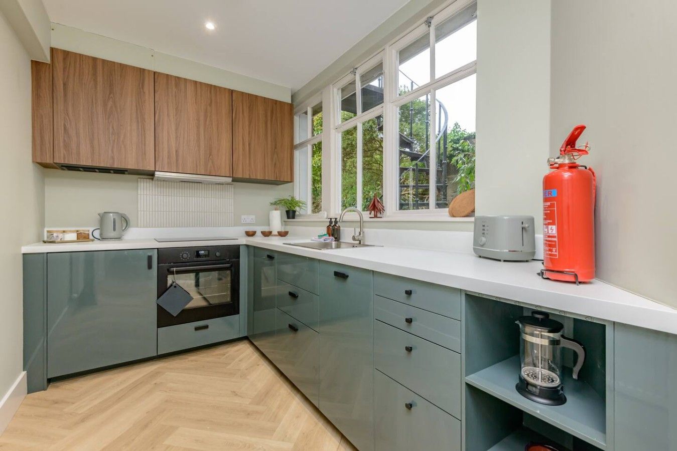 A modern kitchen with a built-in oven, a coffee maker, and a fire extinguisher.