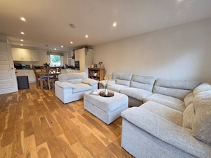 A spacious living area with a sofa set, ottoman, and a dining table with chairs. - Portobello Garden Flat | 2 bed Near Beach (Edinburgh)