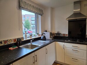 A kitchen with a window, a kettle, and a stove. - Portobello Garden Flat | 2 bed Near Beach (Edinburgh)