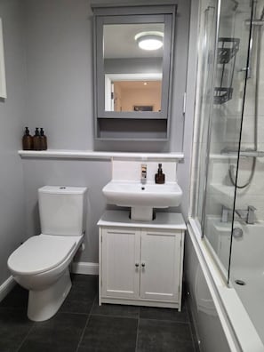 A bathroom with a toilet, a sink, and a shower area. - Portobello Garden Flat | 2 bed Near Beach (Edinburgh)
