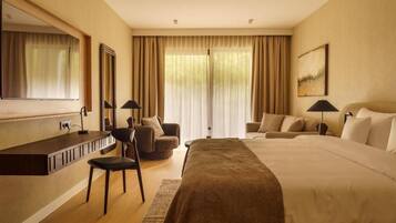 A hotel room with a large bed, a desk with a chair, a sofa, and a large mirror.