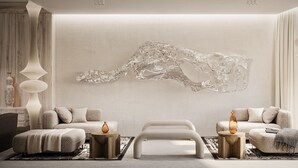 Una sala de estar moderna con una gran escultura abstracta, dos sofás, una mesa de centro y jarrones decorativos.