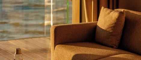 A modern lounge area with a sofa, a round table, and a glass of water.