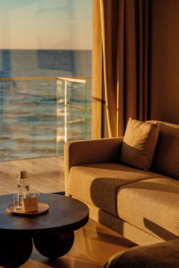 A modern lounge area with a sofa, a round table, and a glass of water.