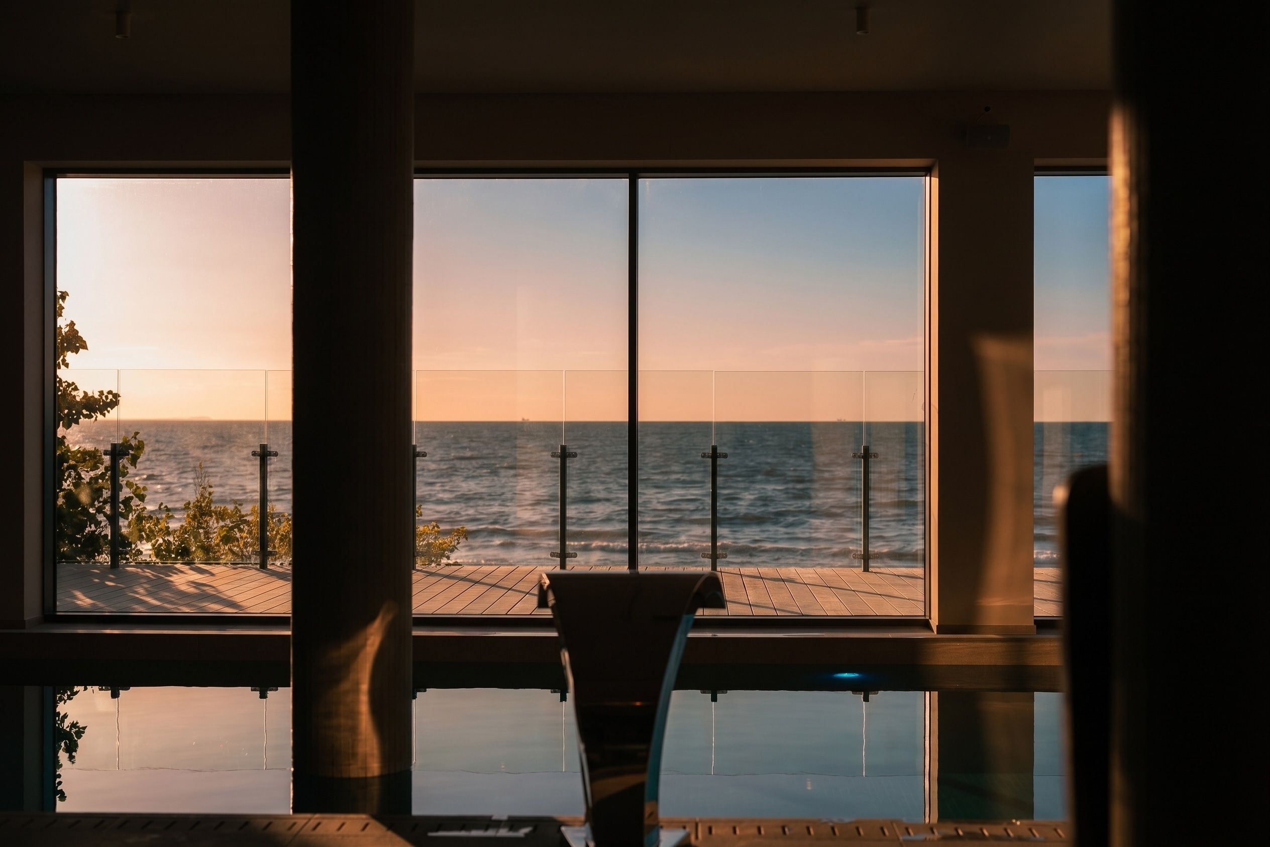 Ein Zimmer mit großem Fenster, das Blick auf ein Gewässer, einen Pool und den Himmel bietet.