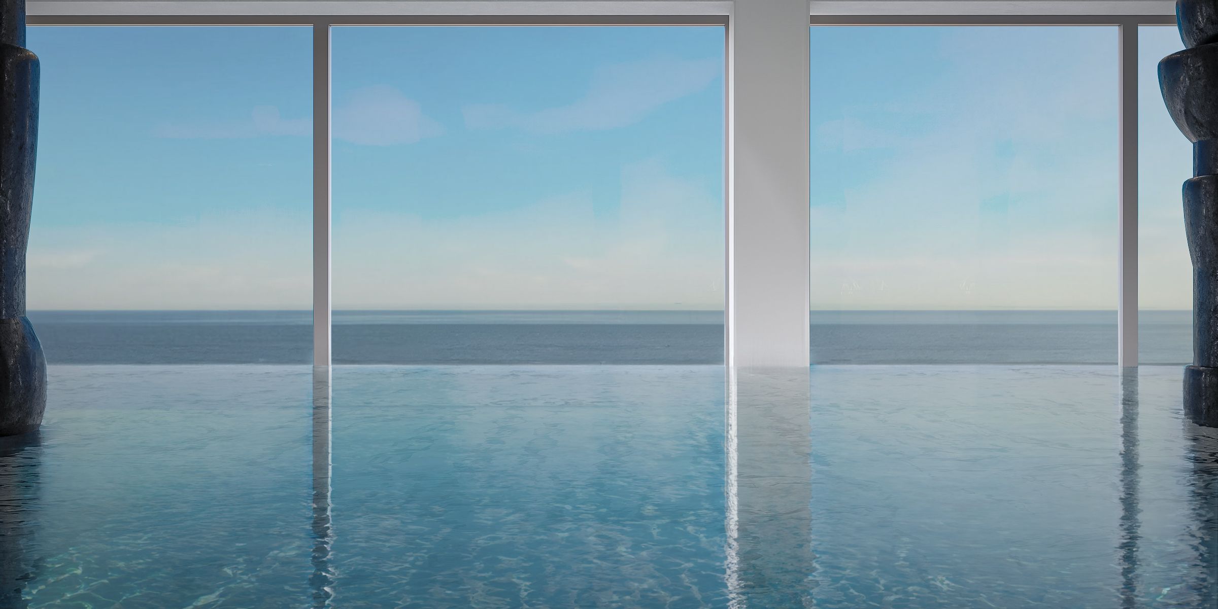 Ein klarer Blick auf einen Pool mit unendlichem Ausblick und Glasboden, umrahmt von weißen Säulen, mit Blick auf ein ruhiges Meer.