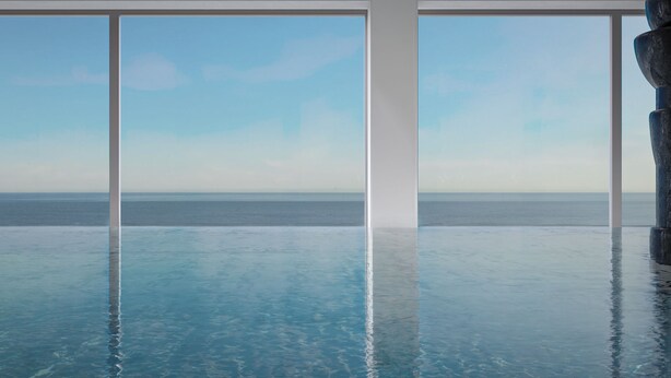 Vista despejada de una piscina infinita con fondo de cristal, enmarcada por pilares blancos, con vistas a un mar tranquilo.