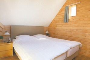 Ein Einzelbett in einem Zimmer mit Holzwänden und schrägem Dach.