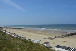 Ein Strand mit einer Holzpromenade, einem Steg und blauem Himmel.