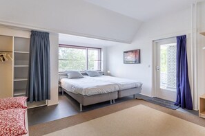 A bedroom with a bed, a wardrobe, a door, and a window. - Domburgseweg 52 Apartment (Oostkapelle)