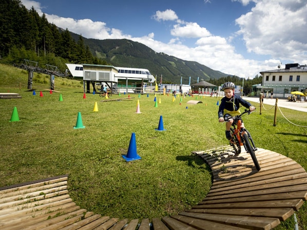 A person riding a bicycle on a wooden ramp with colorful cones arranged on a grassy field.