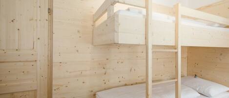 Un letto a castello con una scala, un'armadietto in legno e una parete in legno.