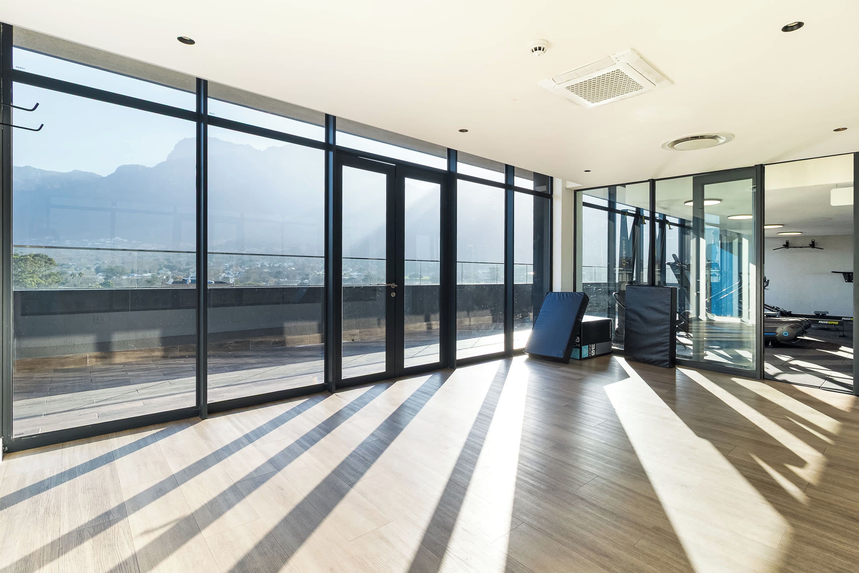 A spacious room with large windows, a view of a cityscape, and a modern interior design.