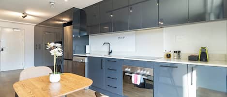 A modern kitchen with grey cabinets, a Bosch oven, and a dining area with a wooden table and chairs.