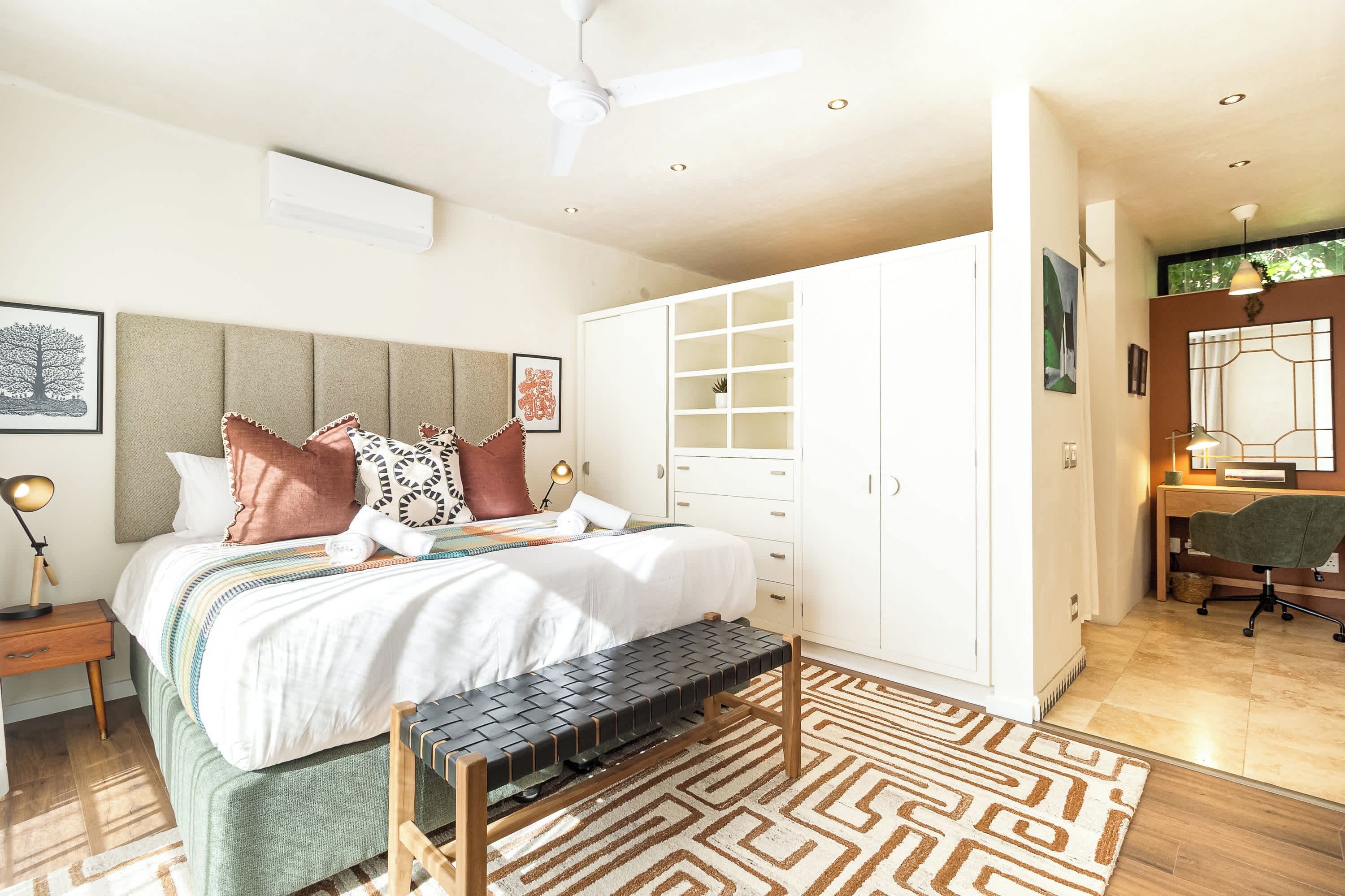 Un dormitorio moderno con una cama, mesita de noche, lámpara y un escritorio con silla.