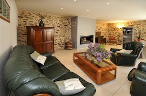Un salon avec un canapé en cuir, une table basse en bois ornée de fleurs, une cheminée et des éléments décoratifs en pierre sur les murs.