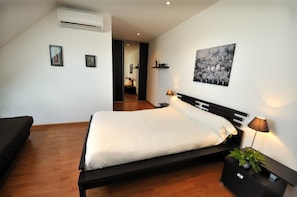 A modern bedroom with a bed, bedside lamps, a small table with a plant, and a zebra artwork on the wall.